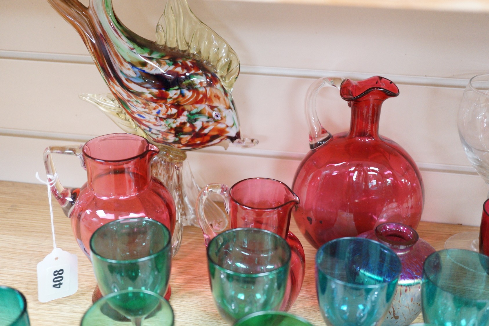 A quantity of cranberry glass, together with other coloured glassware and a Murano style fish ornament